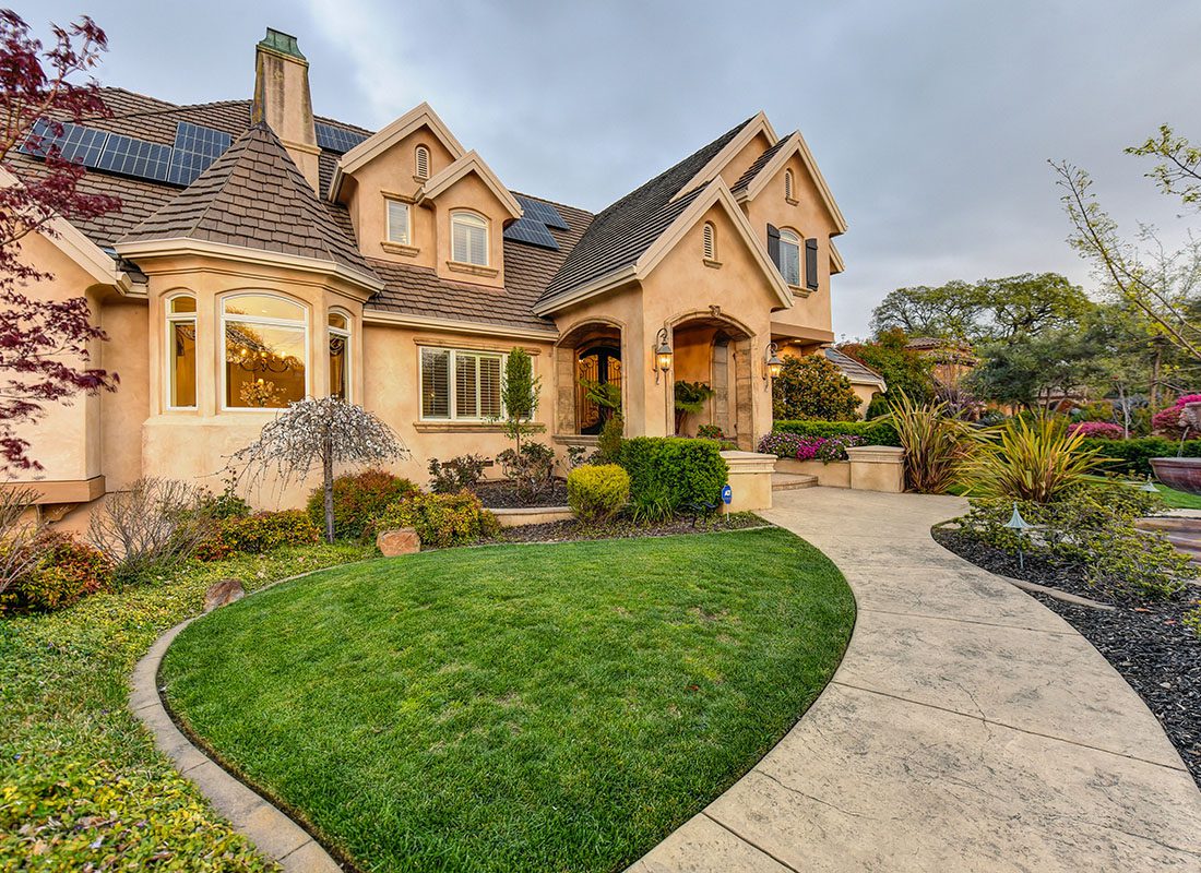 Personal Insurance - Exterior View of a Luxury Two Story Home with a Landscaped Walkway and Plants in the Late Afternoon